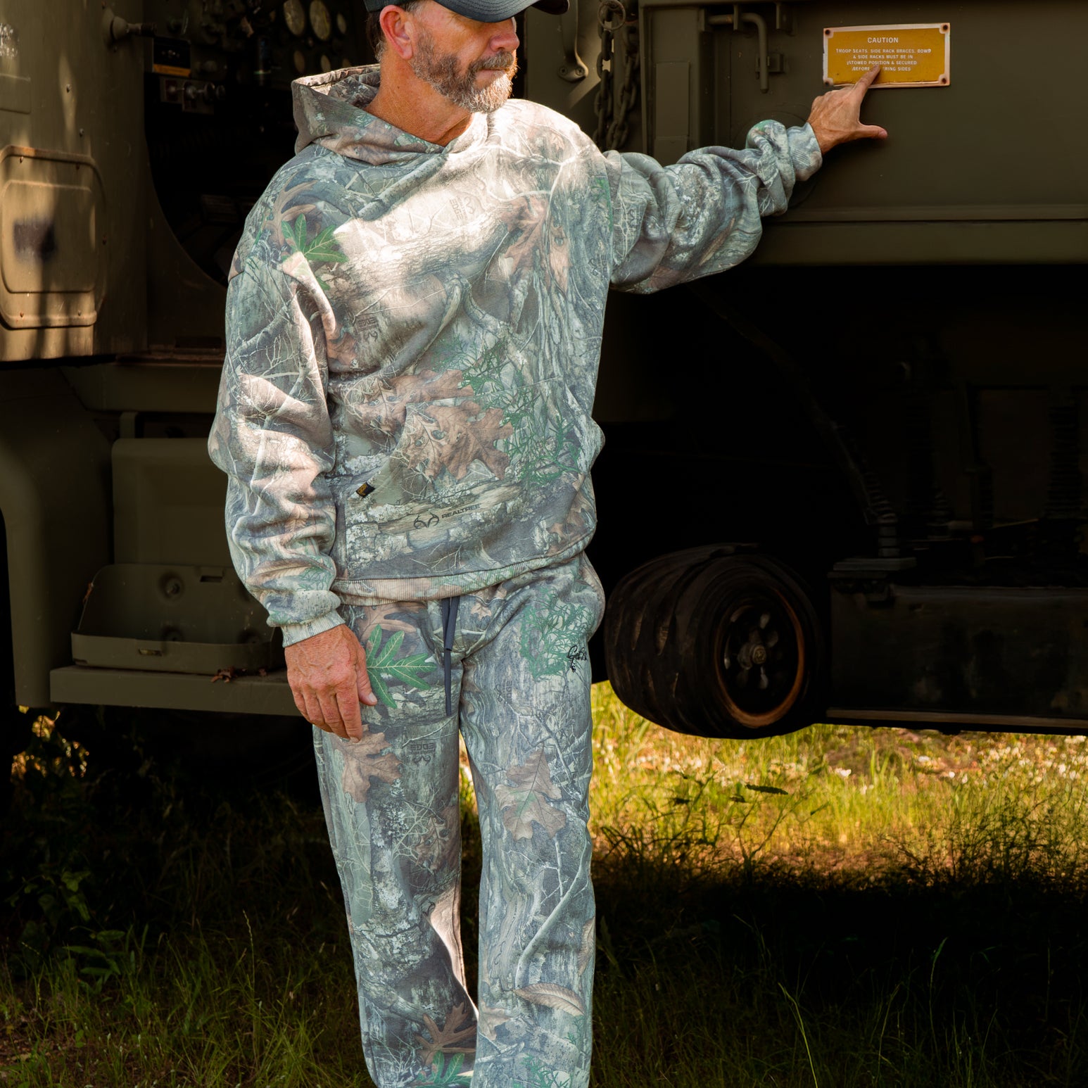 Man in camouflage hoodie and pants outdoors.