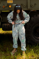 Person wearing camouflage clothing standing in front of a military vehicle.