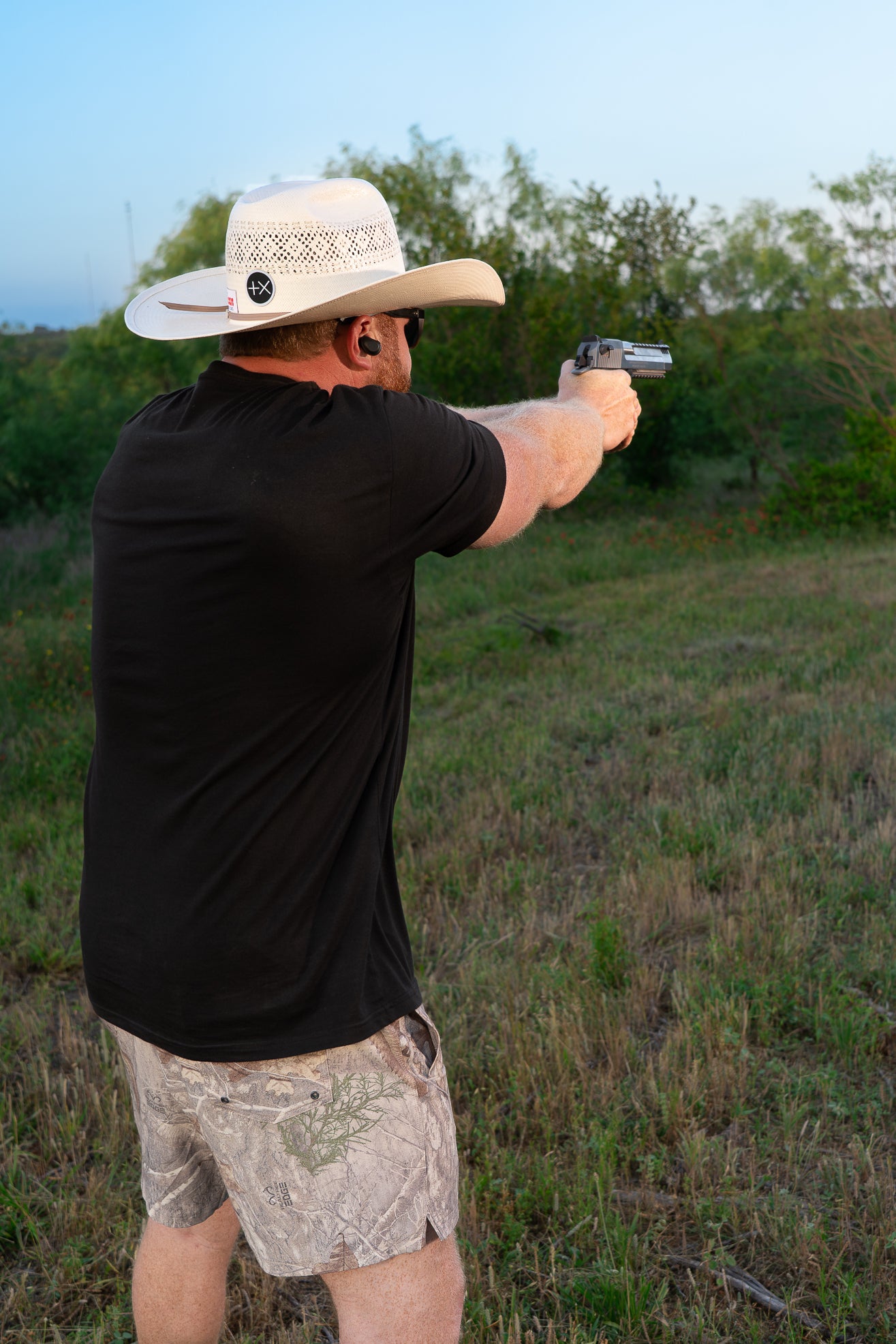 Person shooting gun wearing camo swim trunks