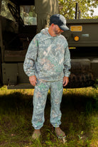 Man in camouflage gear standing in front of a vehicle