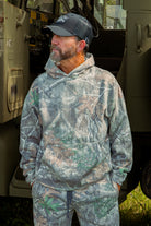 Man wearing a camouflage outfit standing next to a vehicle