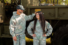 Two people in camouflage hoodies standing in front of a vehicle.
